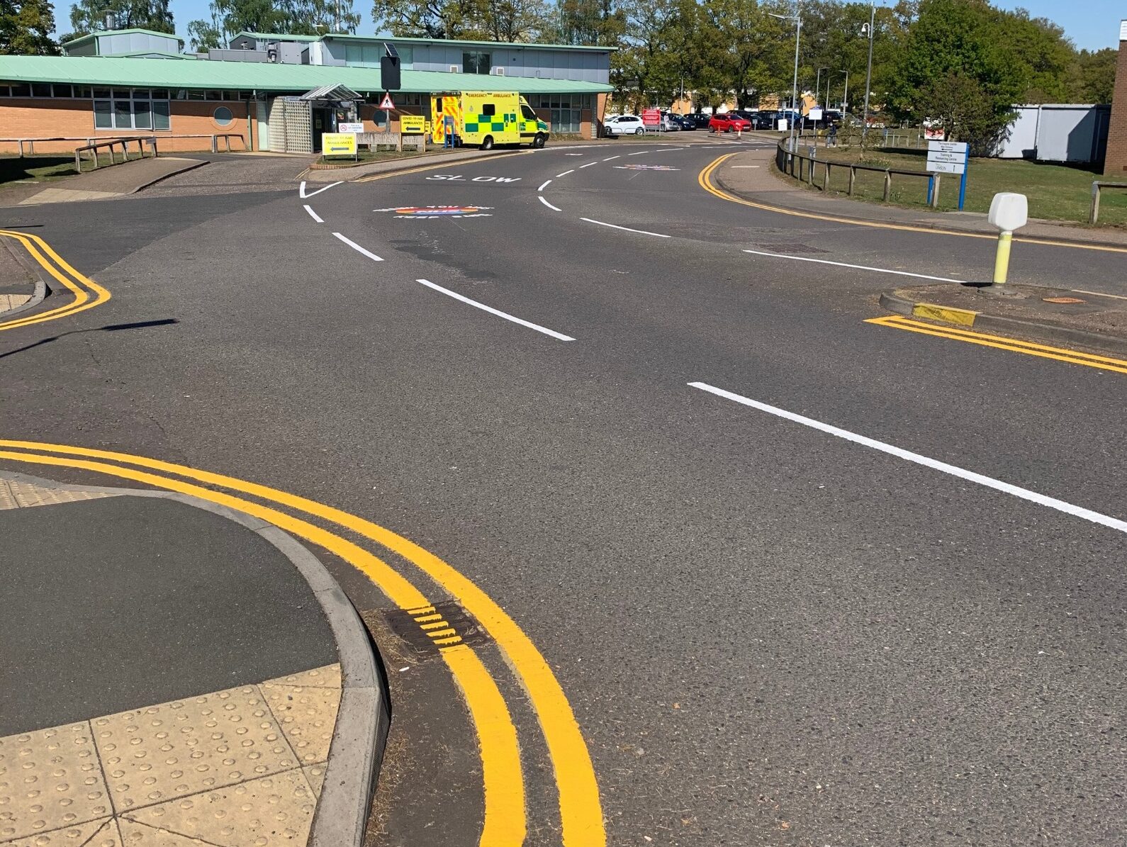 Prismo Guidemaster hot applied thermoplastic road marking used for double yellow lines curving round a road turning, opposite a hospital entrance.