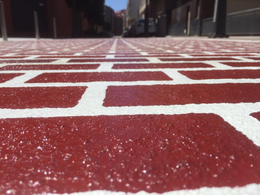Close-up of Urban Patterns from Prismo’s preformed thermoplastic road marking range, showing decorative block paving design with slip-resistant texture in white and chestnut.