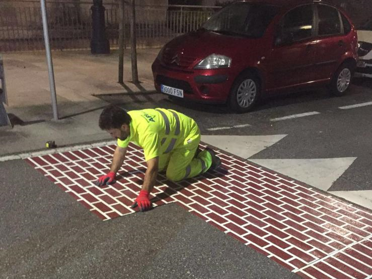 Contractor wearing gloves placing Prismo's Urban Patterns preformed thermoplastic sheets on the road surface by hand