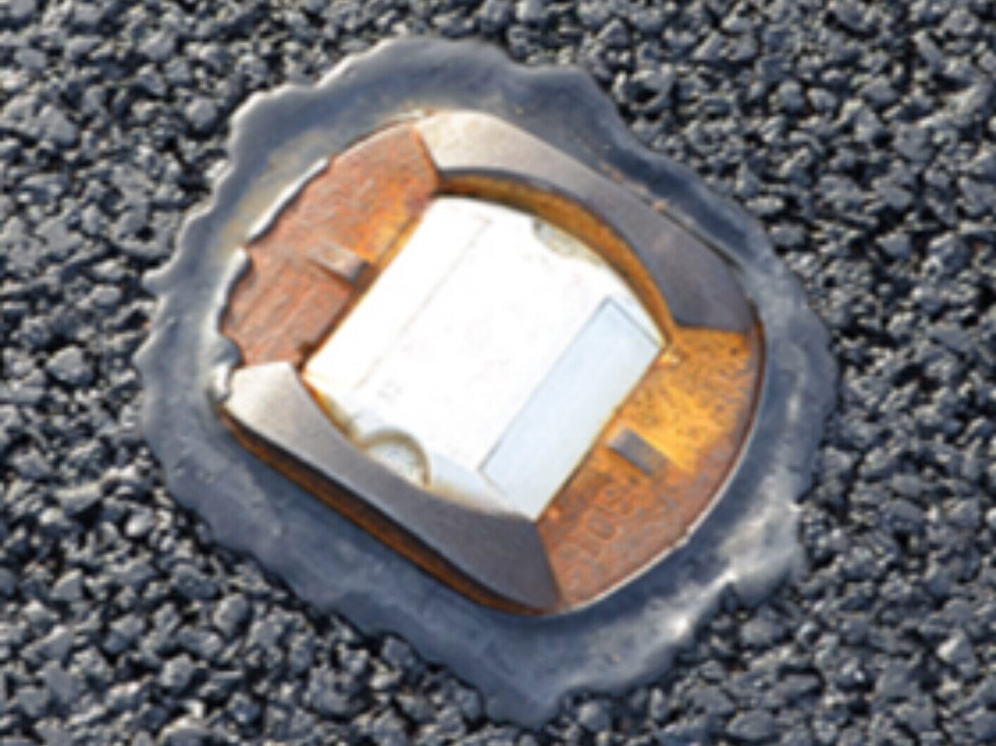 Close-up view of road stud bonded to asphalt using Stimsonite Bitumen Adhesive