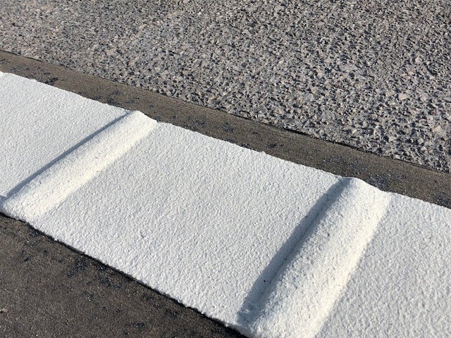 Close-up of Prismo® Vibraline® hot applied thermoplastic applied on road surface as profiled diagonal white line.