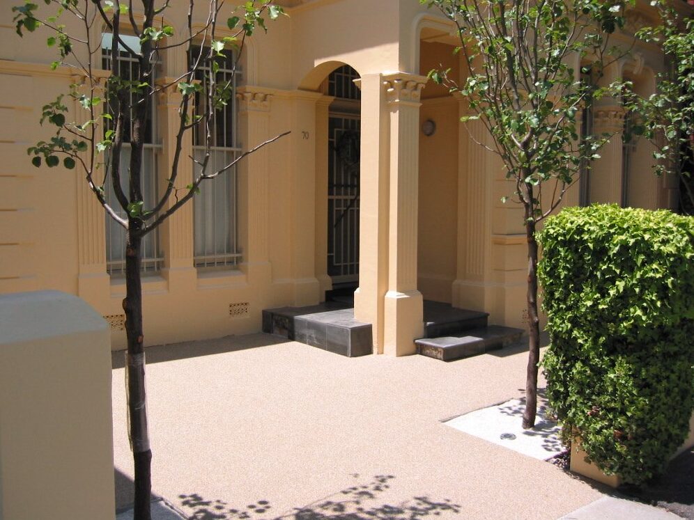 Sunlit pathway in front of a cream house in Australia featuring new Prismo Stonegrip decorative surfacing