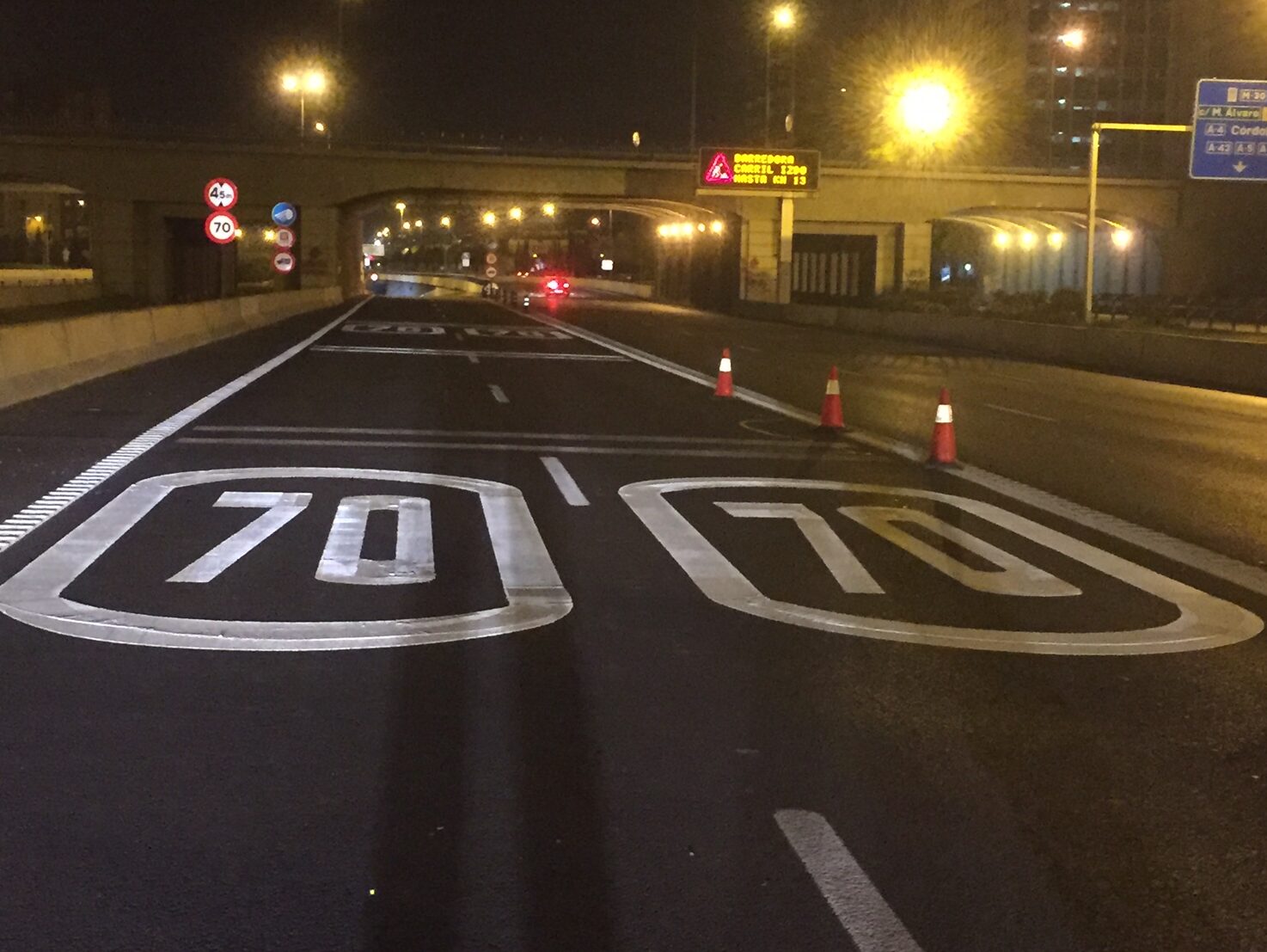 Night view of two motorway lanes with white Prismo® Preformed Thermoplastic 70mph speed limit roundels applied to the road surface.