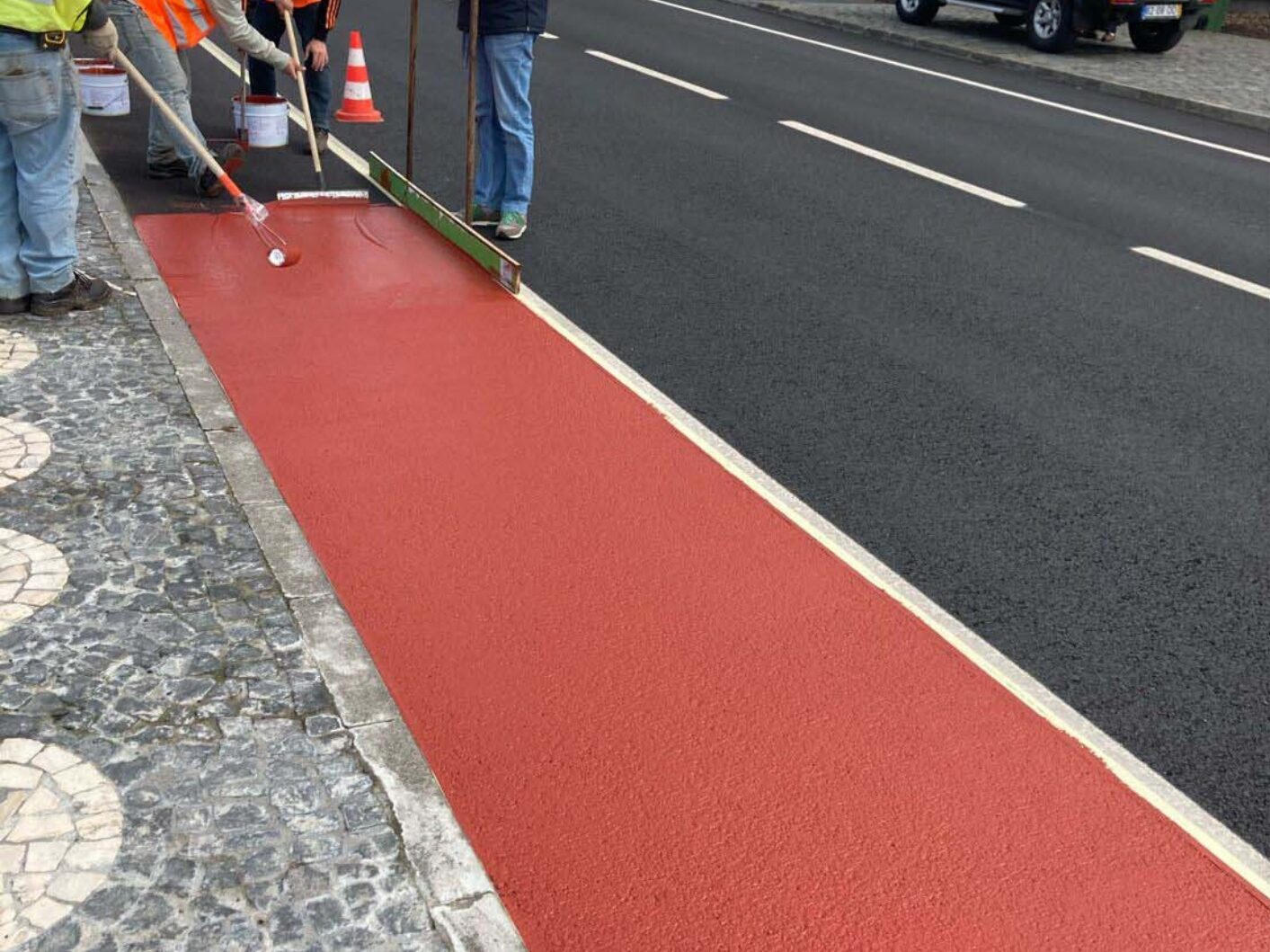 Red Prismo Tyregrip high friction surfacing applied between a main road and a pavement