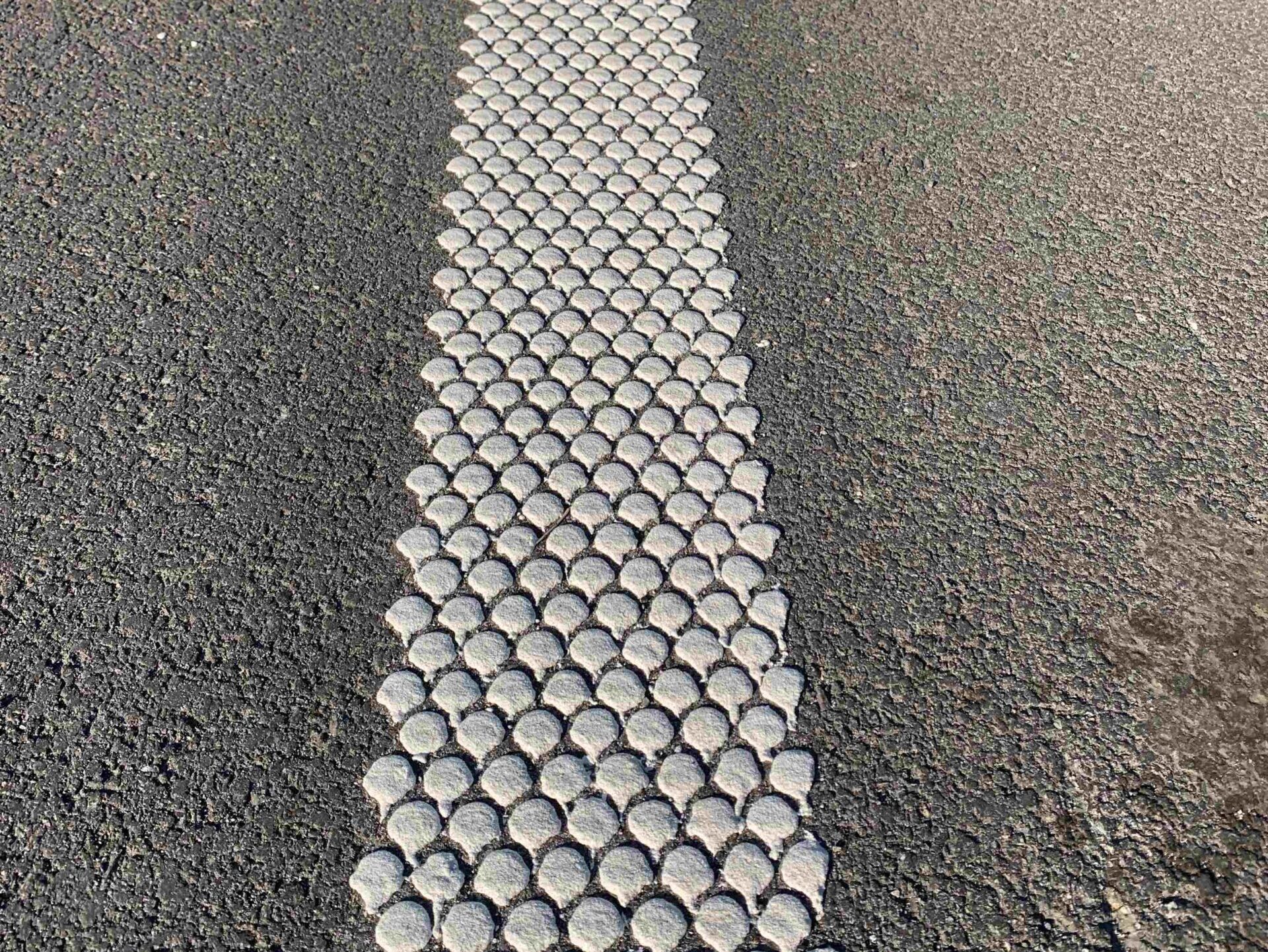 Close-up view of Prismo® Multidot hot applied thermoplastic applied on road surface as dotted line.