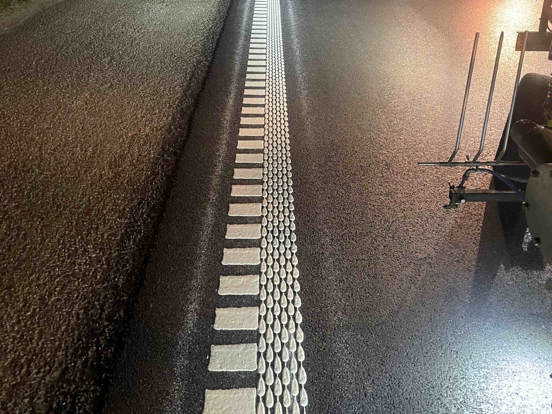 Prismo® Multidot structured hot applied thermoplastic applied as dashed and dotted white lines next to each other on road surface.