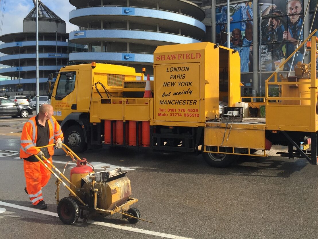 Prismo® Guidemaster® applied as a white line marking on road surface using screed machine outside Etihad football stadium.