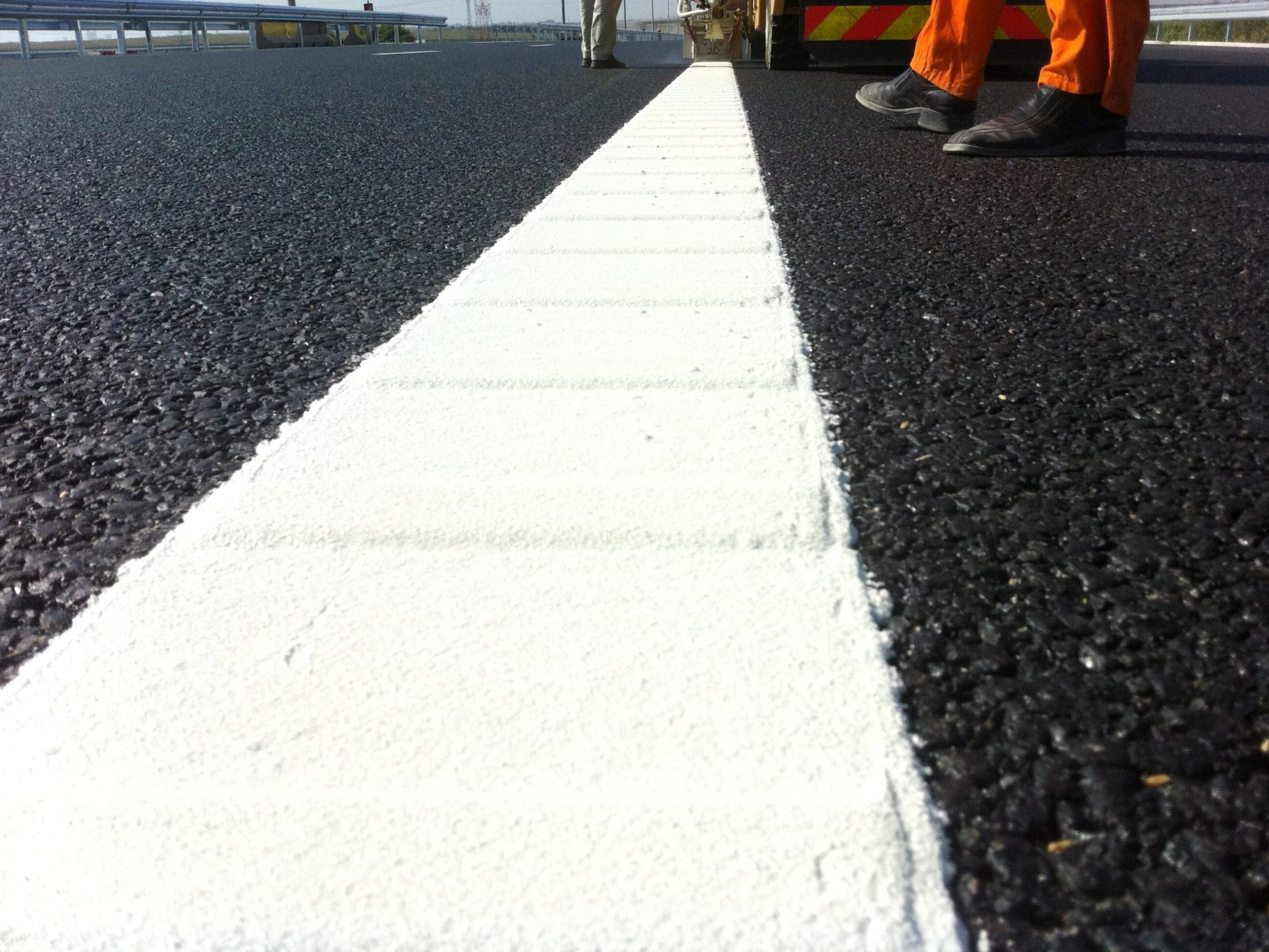 Close-up of Prismo® Vibraline hot applied thermoplastic applied as thick white profiled line marking on road surface.