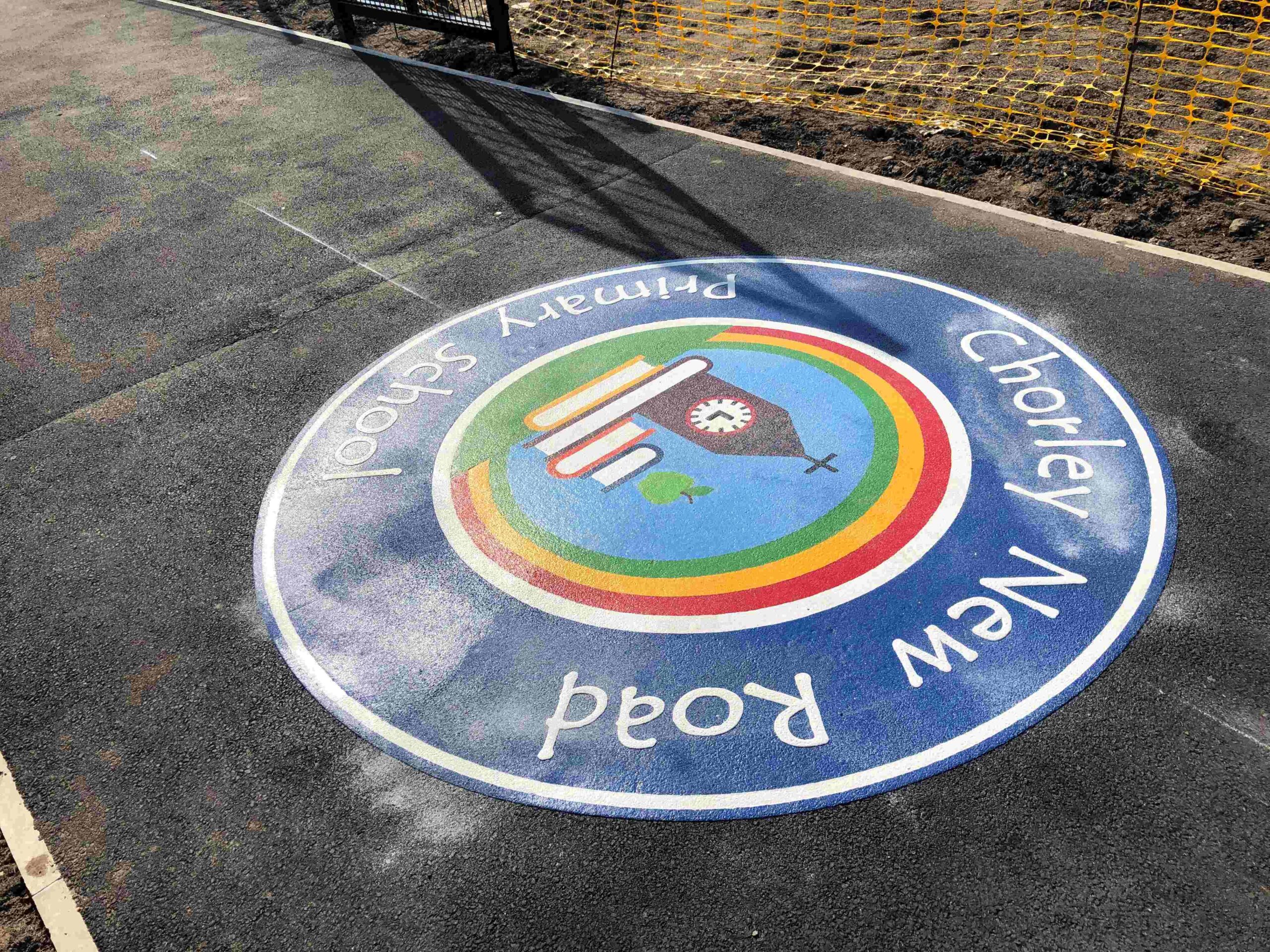 Primary school logo made from Prismo preformed thermoplastic on a pathway, featuring multiple colours with blue as the main school colour.