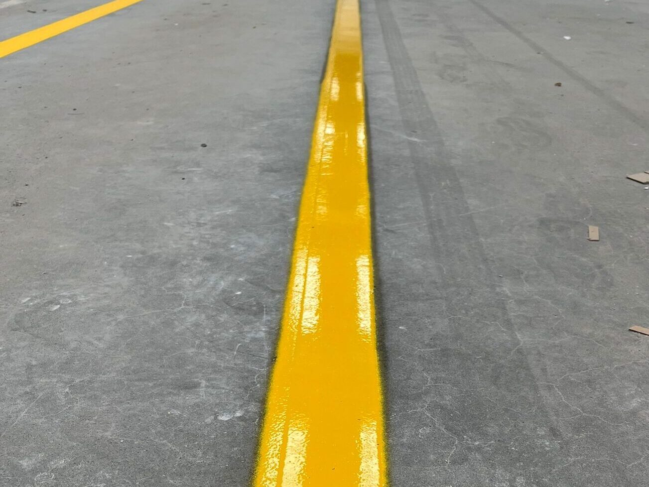 Close-up of Prismo Epoxyline and Acrylic Transparent Paint yellow lines applied on indoor flooring in the UK