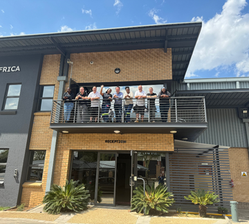 The Prismo® team standing together on a balcony outside a company building
