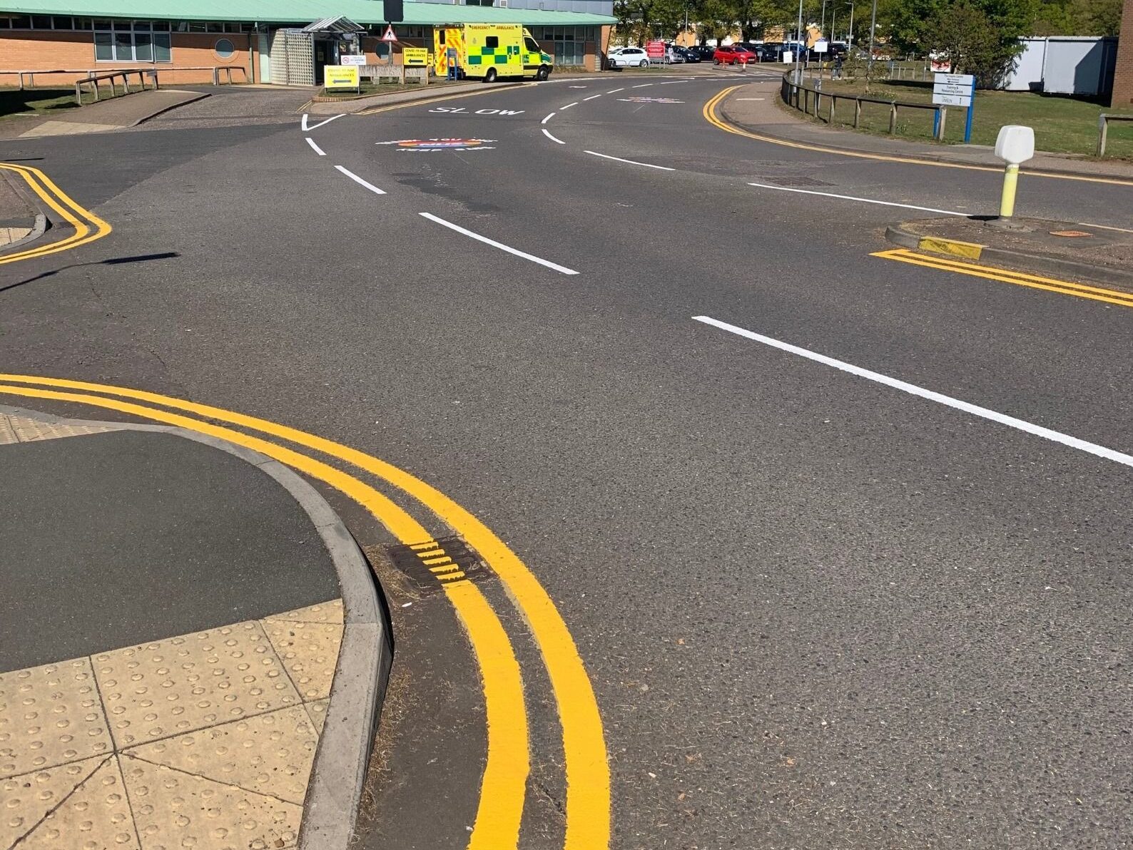 Prismo Guidemaster hot applied thermoplastic road marking used for double yellow lines curving round a road turning, opposite a hospital entrance.
