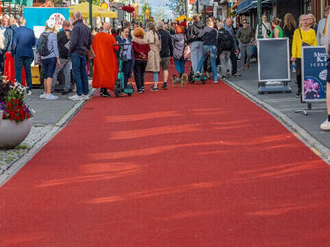 Pedestrians walking on red Prismo Tyregrip high friction surfacing on a busy street in Reykjavík.