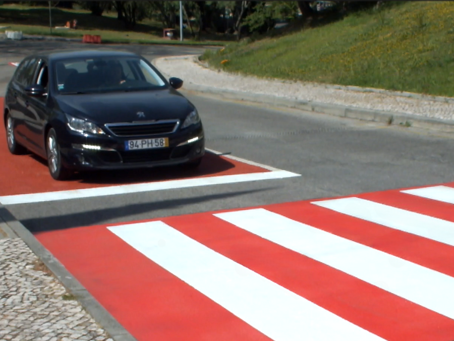 Red Prismo Tyregrip high friction surfacing at a pedestrian crossing in Portugal with a car approaching.