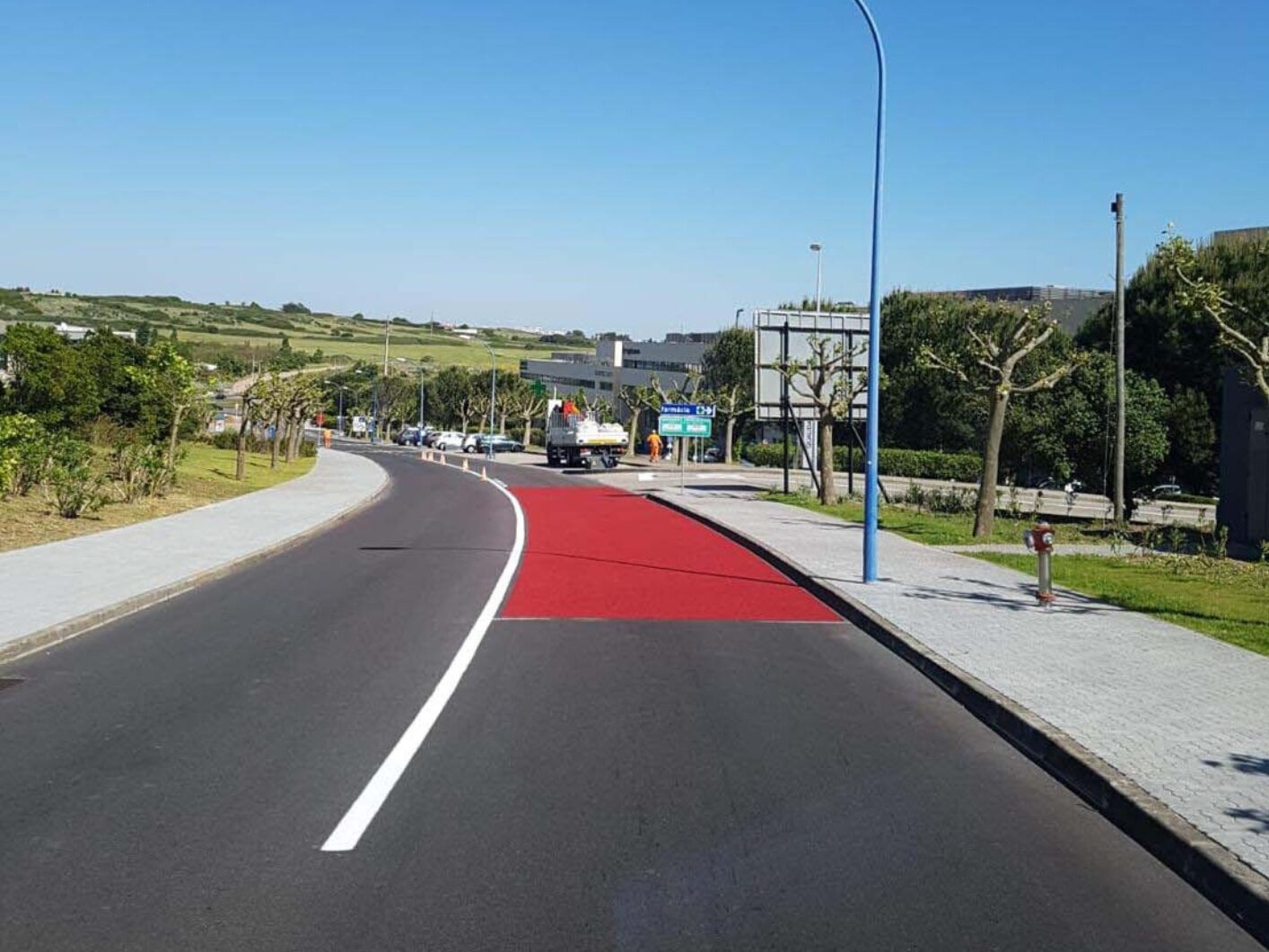 Red Prismo Tyregrip high friction surfacing applied to a main road on a clear, sunny day